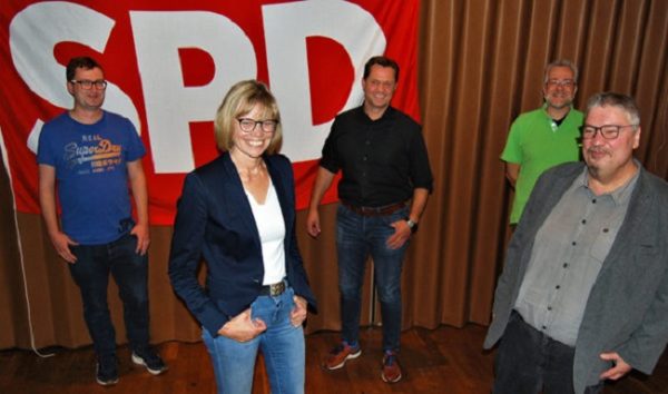 Mehrere Personen stehen vor einer SPD-Flagge.