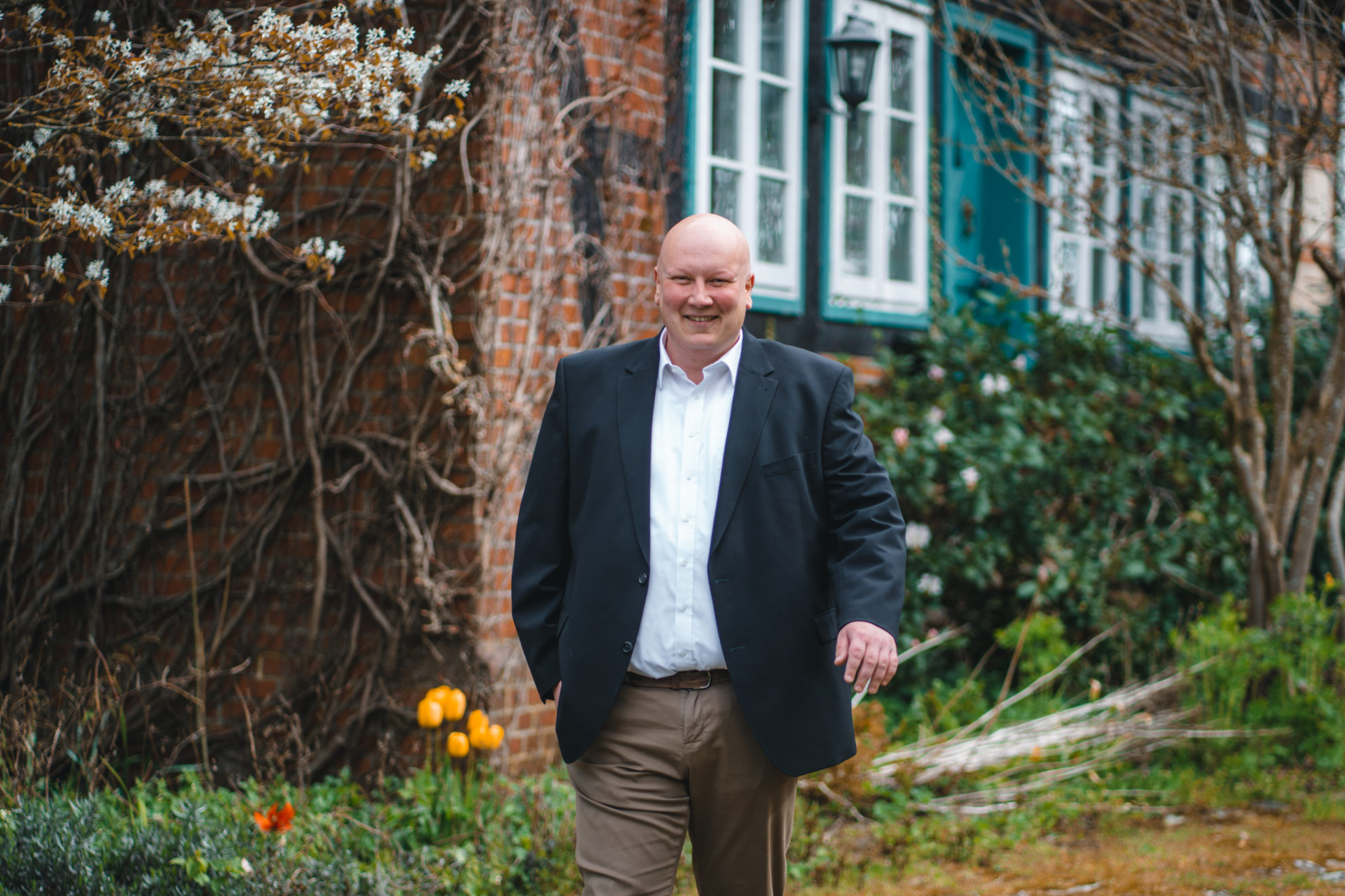 Felix Gieske-Wollerich steht vor einem alten Fachwerkhaus. Er trägt ein weißes Hemd und darüber ein schwarzes Sakko.